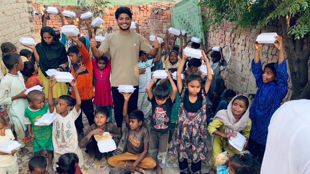 Moheeb Ashraf with children holding meal boxes